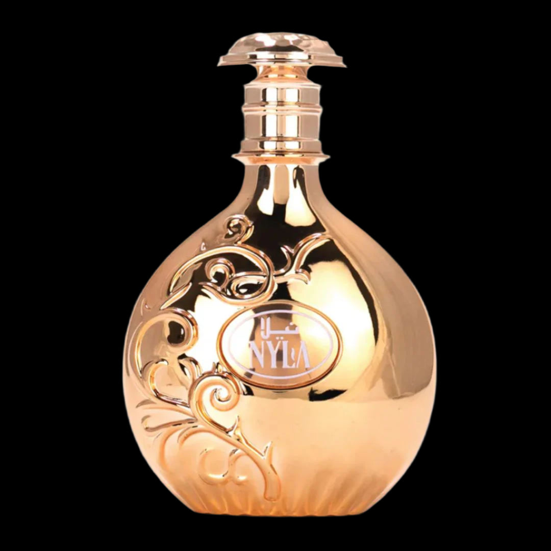 alt="Nyla perfume by Arabiyat Prestige – elegant rose gold bottle with floral engravings, surrounded by coconut shells, peach slices, tiare blossoms, and vanilla pods, representing a tropical fruity floral feminine fragrance available at Parfum Zone KE"