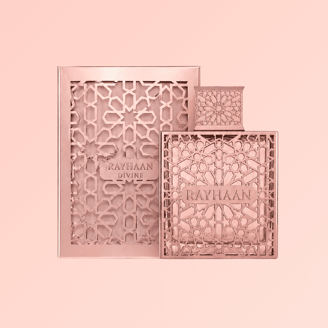 Rayhaan Divine perfume bottle and matching decorative box in a metallic rose gold finish, set against a solid pale pink background.