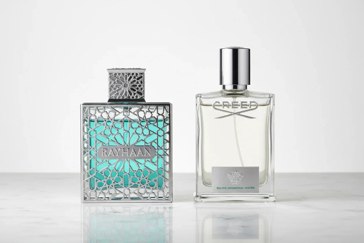 Two luxury perfume bottles, Rayhaan and Creed Silver Mountain Water, on a marble surface.